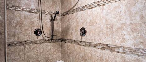 A bathroom with a shower, two faucets, and a bathtub.