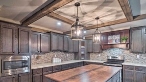 A kitchen with dark wood cabinets, a large island, stainless steel appliances, and a stone backsplash. - Waterfront Louisiana Vacation Rental w/ Dock! (Many)