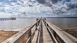 A wooden pier extending into calm water under a partly cloudy sky. - Waterfront Louisiana Vacation Rental w/ Dock! (Many)