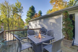 Une terrasse avec une table carrée et quatre chaises, un foyer extérieur et un pot de fleurs.