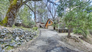 A rustic cabin with a stone wall and a wooden deck, surrounded by trees. - 'lakeside Bear Lodge' Studio: 9 Mi to Bass Lake! (Wishon)
