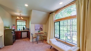 A cozy room with a large window, a bench, a dining area with a table and chairs, and a kitchen area with a refrigerator and a sink. - 'lakeside Bear Lodge' Studio: 9 Mi to Bass Lake! (Wishon)