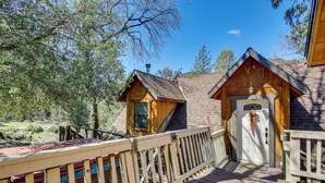 A wooden cabin with a deck, a chimney, and a door with a hanging ornament. - 'lakeside Bear Lodge' Studio: 9 Mi to Bass Lake! (Wishon)