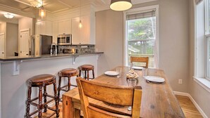 Una cocina con armarios blancos, una mesa de comedor de madera y taburetes de bar.