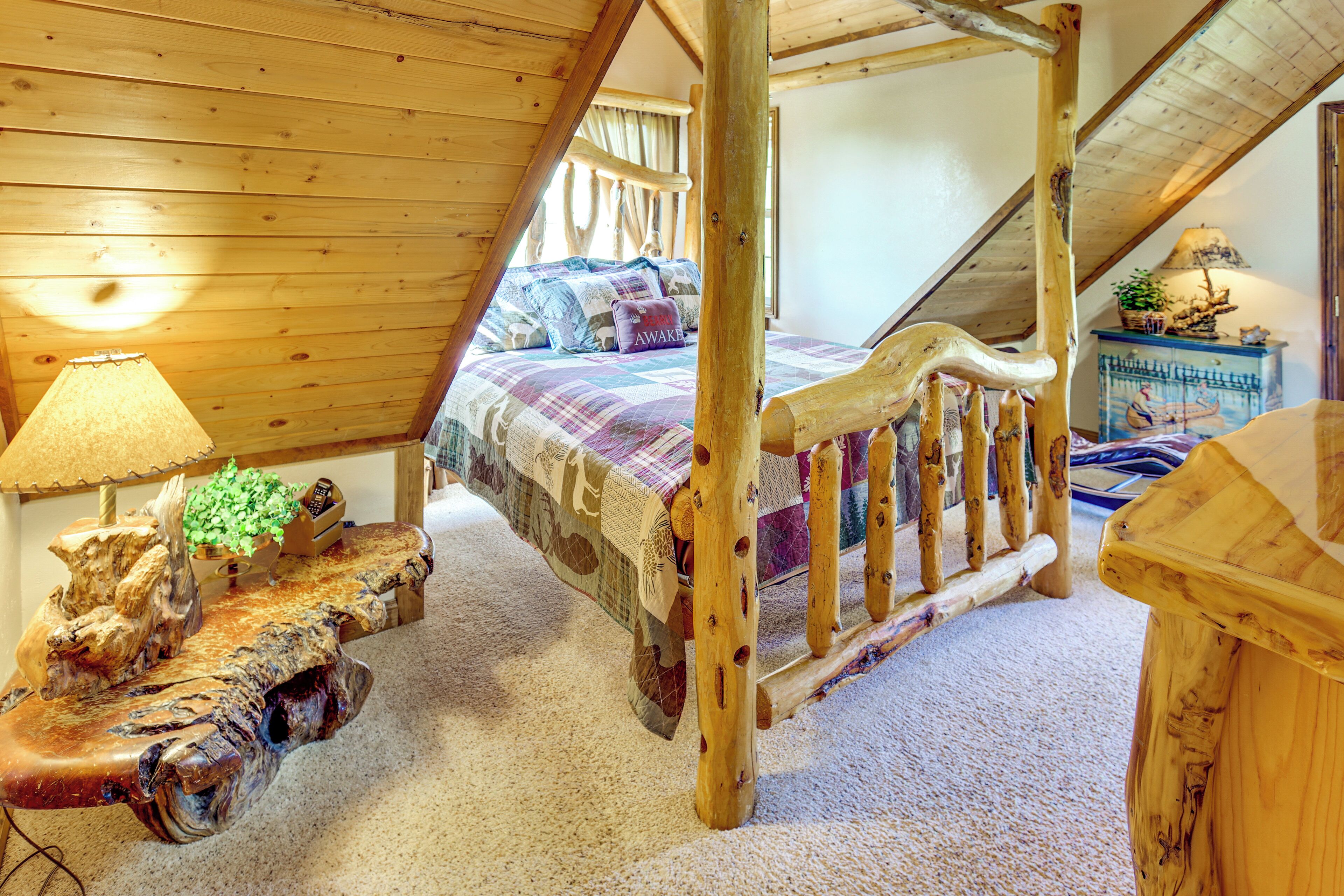 A cozy attic bedroom with a wooden bed, a nightstand with a lamp, and a rustic wooden dresser.