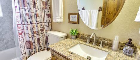 A bathroom with a toilet, sink, and shower curtain.