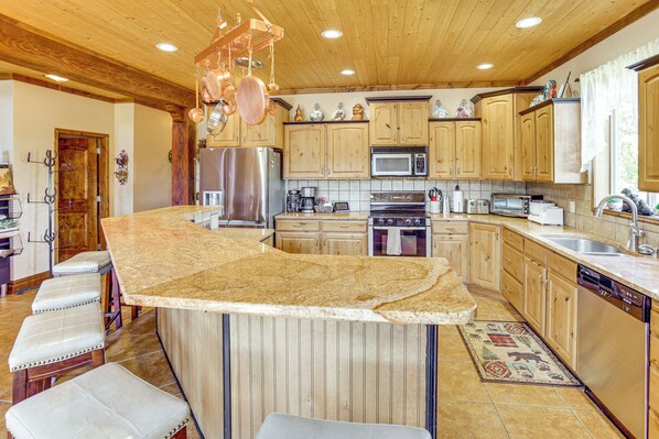 A spacious kitchen with wooden cabinets, stainless steel appliances, and a granite countertop.