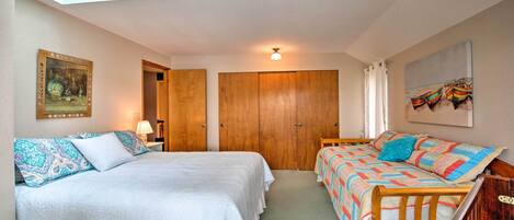 A bedroom with two beds, a skylight, a wooden wardrobe, a painting, and a window with curtains.