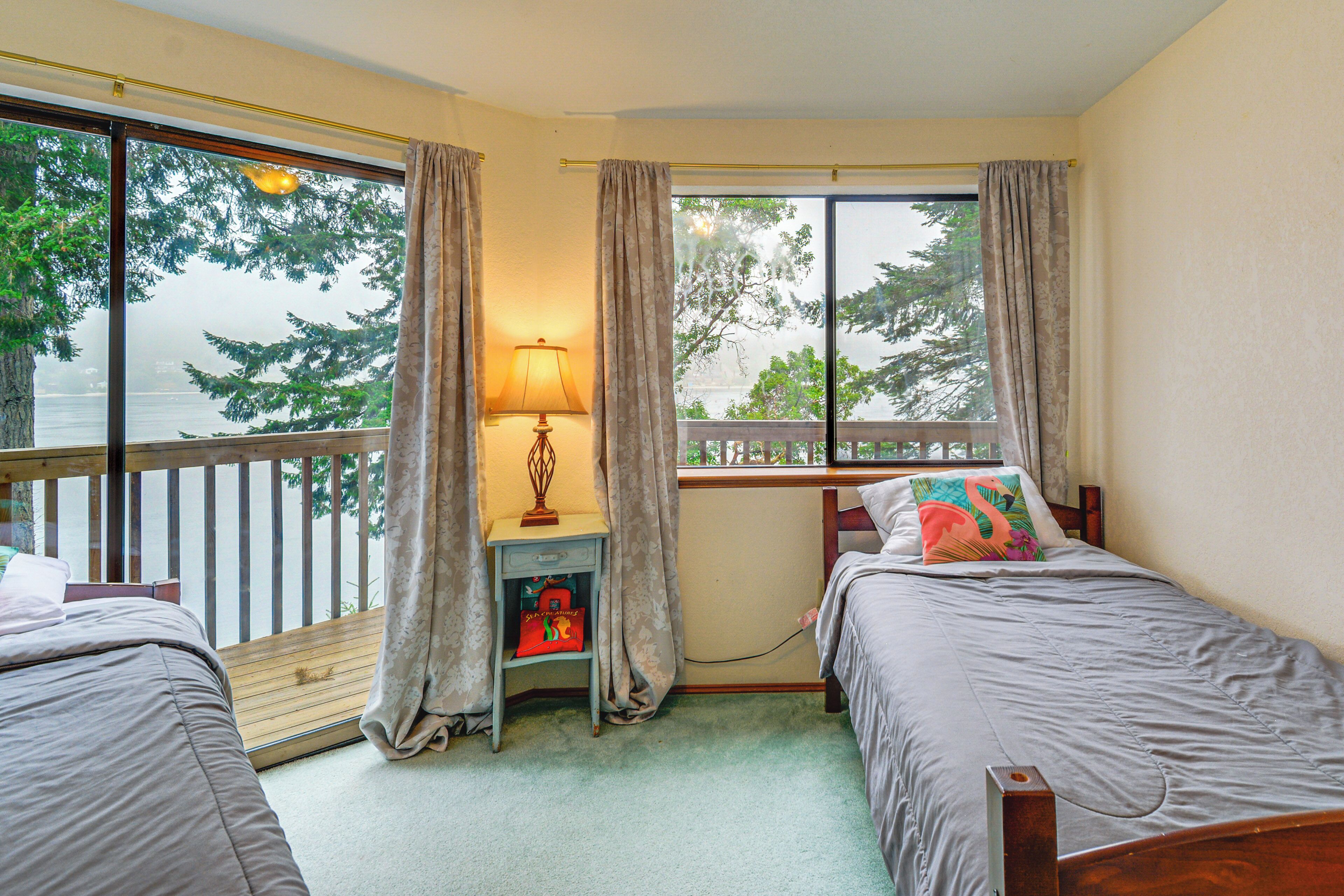 A bedroom with two beds, a nightstand, a lamp, and a window with curtains.