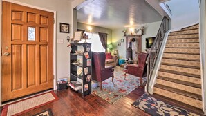 A wooden door, a bookshelf, a red armchair, a patterned rug, and a staircase. - Charming Cedar City Retreat - Walk to Downtown! (Cedar City)