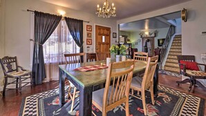 A dining area with a wooden table, chairs, and a chandelier. There is a staircase leading to another room. - Charming Cedar City Retreat - Walk to Downtown! (Cedar City)