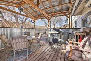 A covered outdoor patio with wooden furniture, a grill, and a decorative fence. - Charming Cedar City Retreat - Walk to Downtown! (Cedar City)