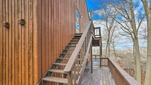 Una scala in legno conduce a un edificio con vista su alberi e un cielo sereno.