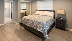Une chambre à coucher avec un lit, une table de chevet, une fenêtre et une porte.