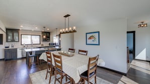 A modern kitchen with a central island, wooden chairs, and a dining table. - Pet-friendly Victor Home w/ Fire Pit & Large Yard! (Victor)