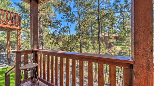 A wooden deck with a metal chair, overlooking a forested area with a clear sky. - Alto Adventure Base w/ Deck: Hike, Bike & Ski! (Alto)