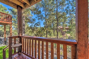 A wooden deck with a metal chair, overlooking a forested area with a clear sky. - Alto Adventure Base w/ Deck: Hike, Bike & Ski! (Alto)