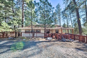 A cabin with a wooden deck, surrounded by tall pine trees. - Spacious Ruidoso Cabin < 3 Mi to Downtown! (Ruidoso)