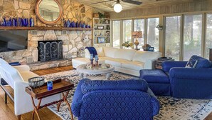 A living room with a stone fireplace, white sofa, blue armchairs, and a coffee table. - Dobson Getaway w/ Private Pool & Game Room! (Dobson)