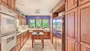 A kitchen with wooden cabinets, stainless steel appliances, and a window with a view of greenery. - Dobson Getaway w/ Private Pool & Game Room! (Dobson)