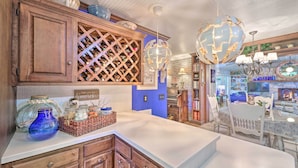 A kitchen with wooden cabinets, a wine rack, and a dining area with a table and chairs. - Dobson Getaway w/ Private Pool & Game Room! (Dobson)