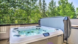 Un jacuzzi extérieur doté d’un panneau de commande, entouré d’arbres.