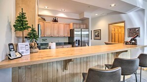 Une cuisine moderne avec des meubles en bois, un réfrigérateur en acier inoxydable et un comptoir-bar en bois, agrémenté de tabourets de bar.