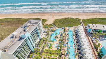 Un resort con una amplia zona de piscina, varias piscinas y vista al mar.