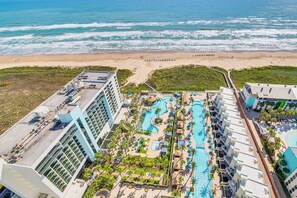 A resort with a large pool area, multiple swimming pools, and a beach view.