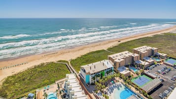 Un resort con vista a la playa, varias piscinas y un estacionamiento.