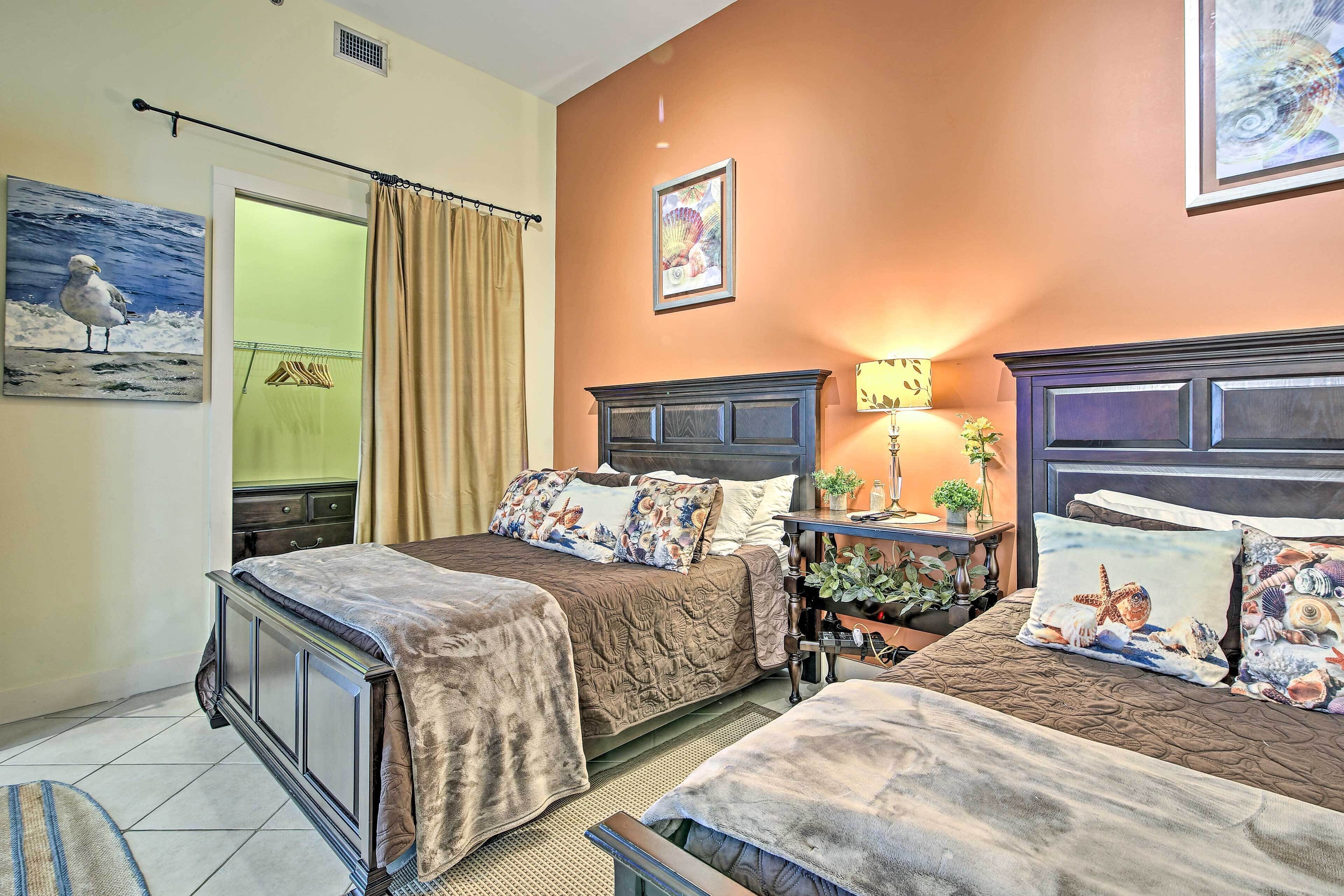 Quarto de hotel com duas camas, uma mesa de cabeceira, uma luminária e um quadro de uma gaivota.