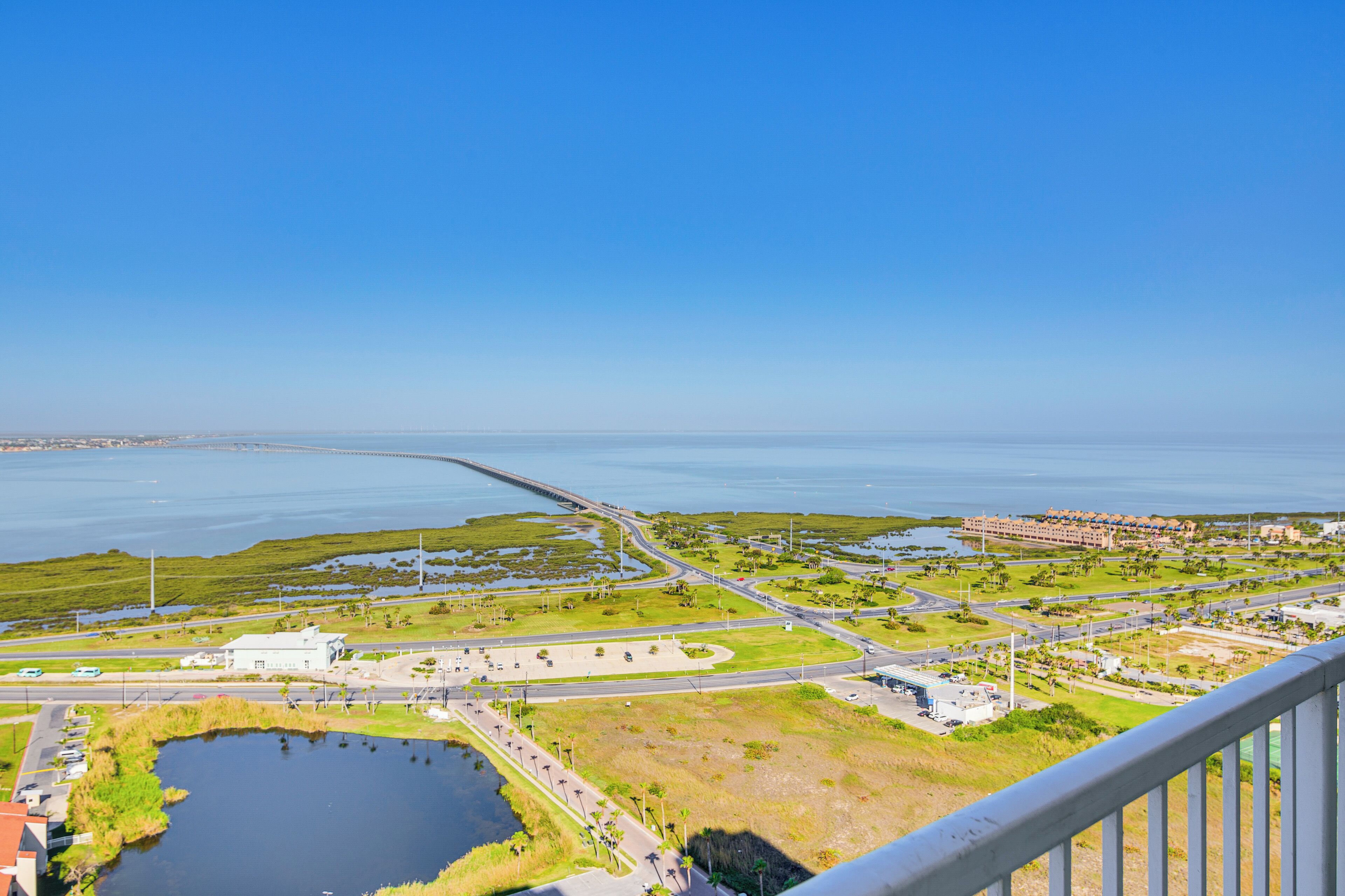 An aerial view of a coastal area with a bridge, roads, and buildings.