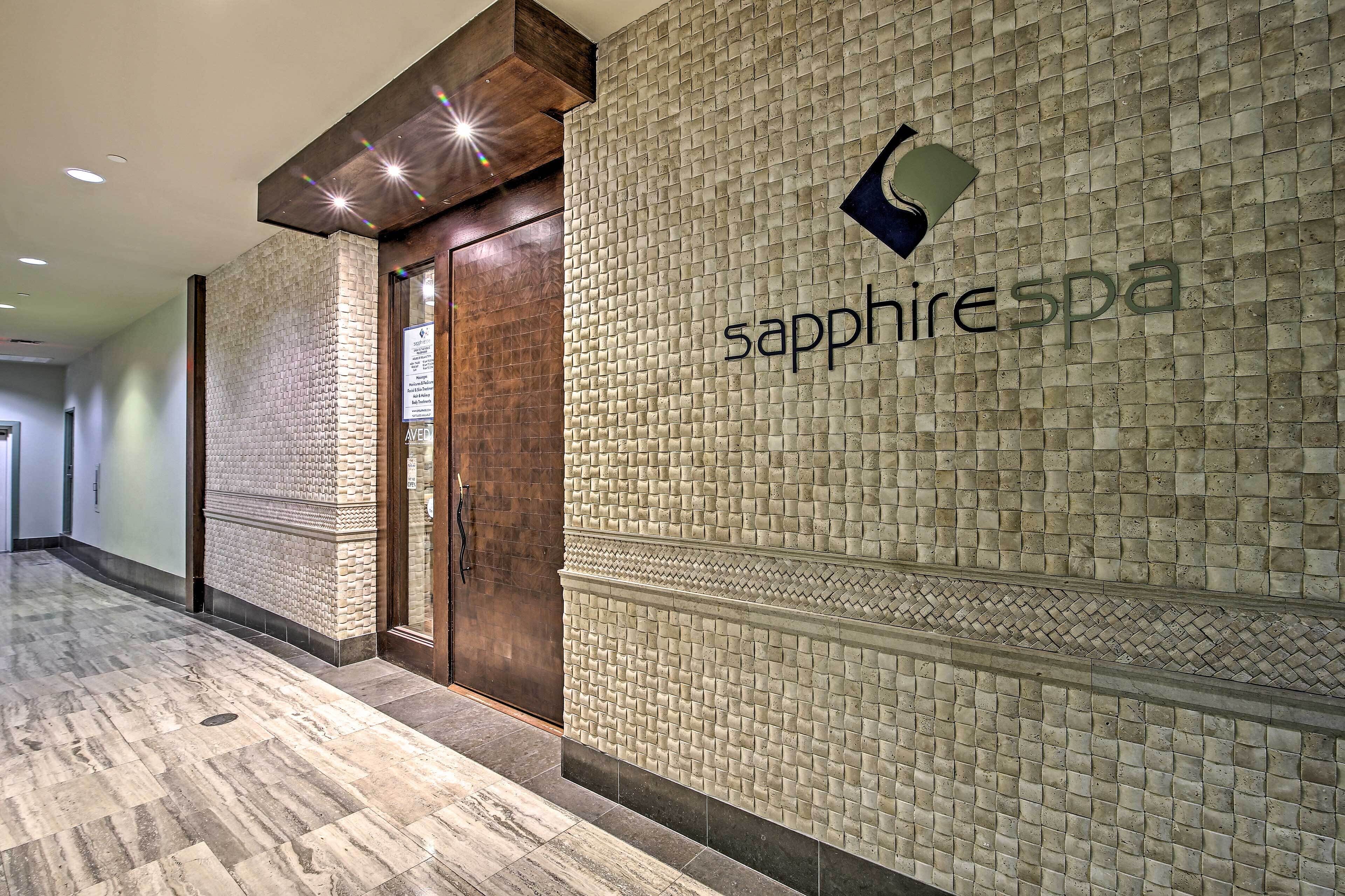 Un couloir avec un mur à texture et une porte portant l’inscription « spa Saphir ».