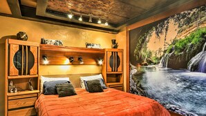 A bedroom with a large bed, wooden headboard, bedside tables, and a mural of a waterfall. - Willamette Valley Apt - Surrounded by Wineries! (Hillsboro)