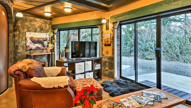 A cozy living room with a leather sofa, a coffee table with magazines, a TV, and a fireplace. - Willamette Valley Apt - Surrounded by Wineries! (Hillsboro)