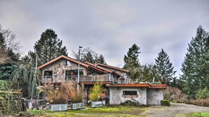 A two-story stone house with a balcony, surrounded by trees and a gravel driveway. - Willamette Valley Apt - Surrounded by Wineries! (Hillsboro)