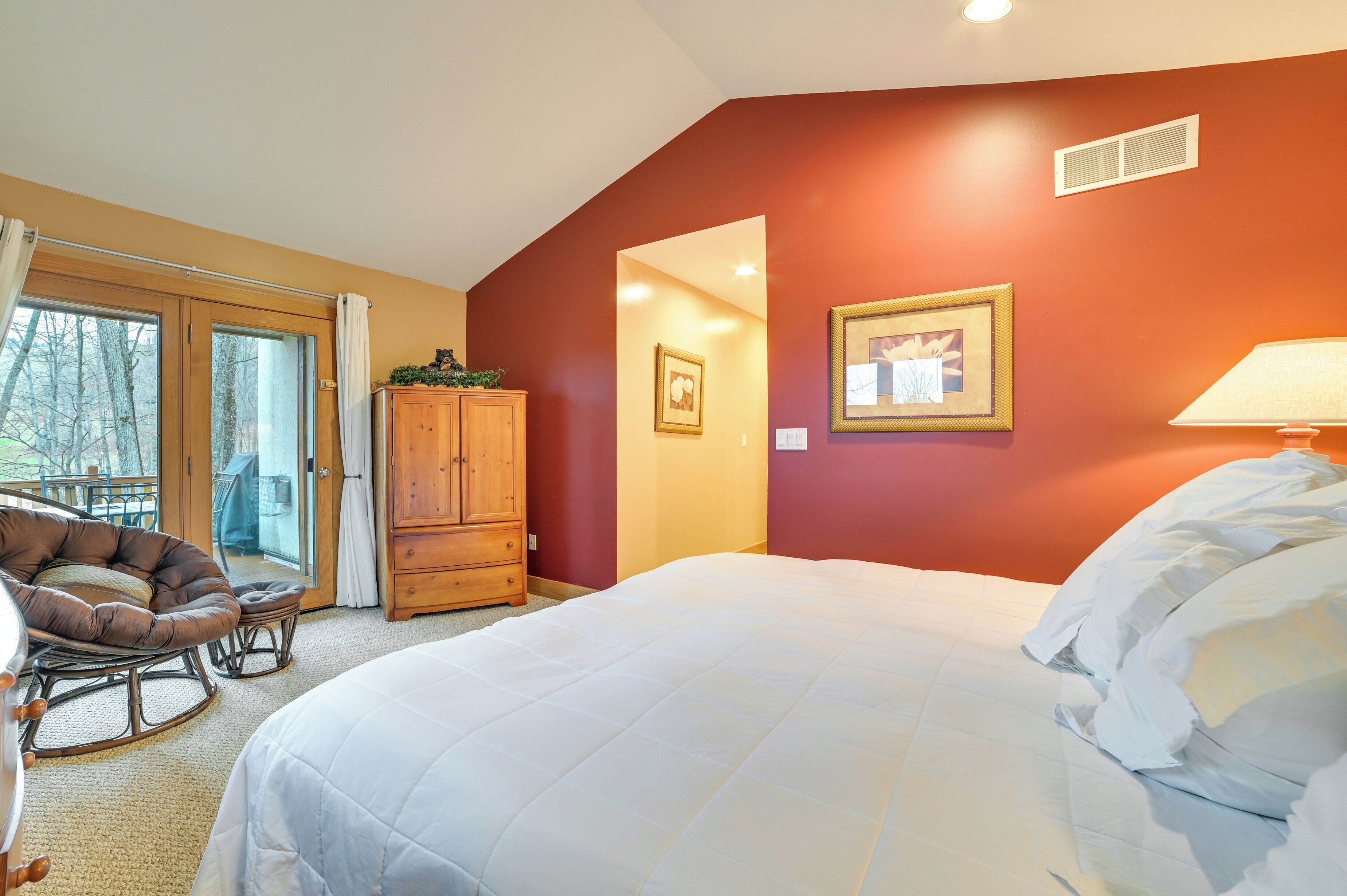 A bedroom with a bed, a wooden wardrobe, a chair, and a framed picture on the wall.