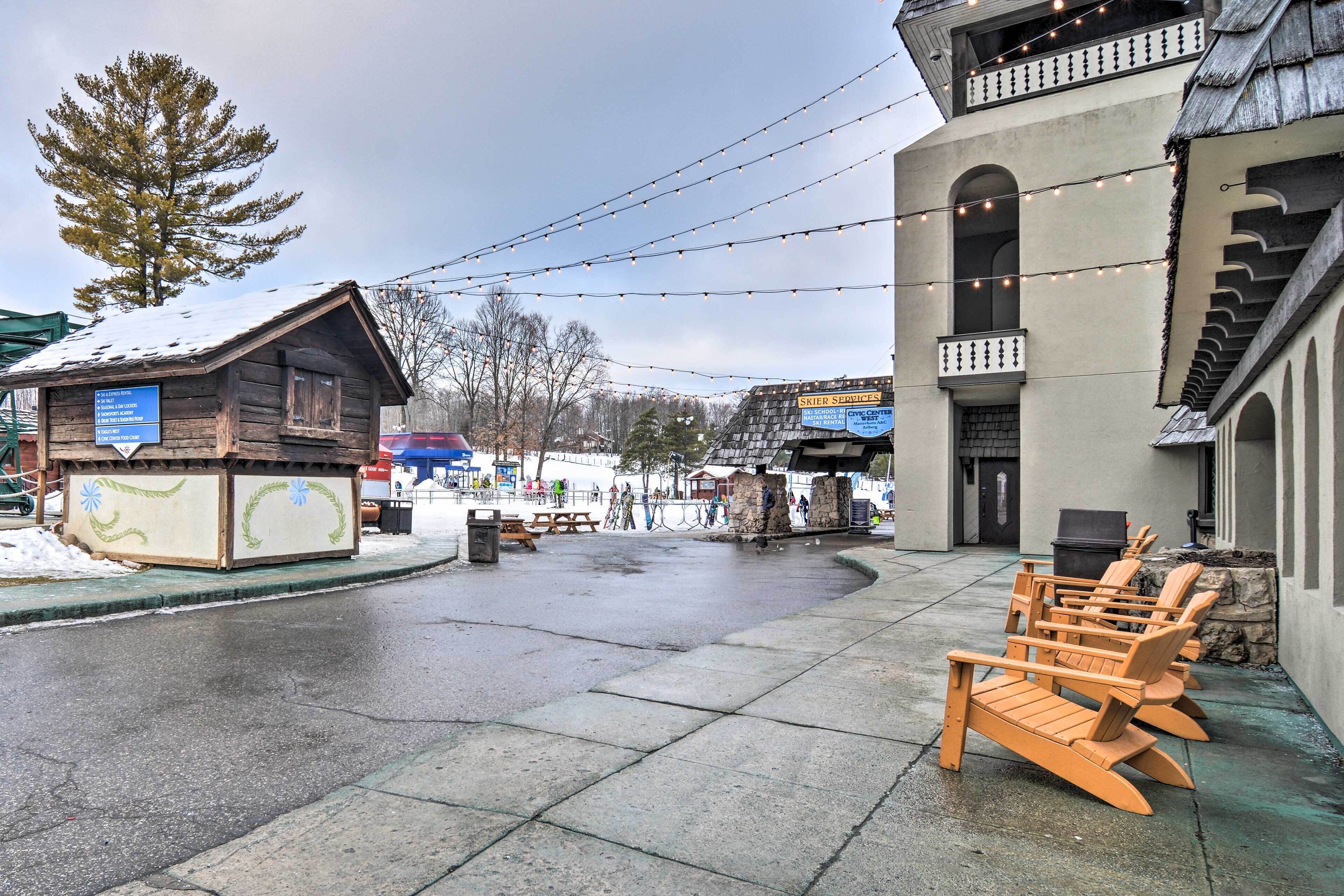 A wooden building with a signboard, outdoor seating, and a snow-covered ground.
