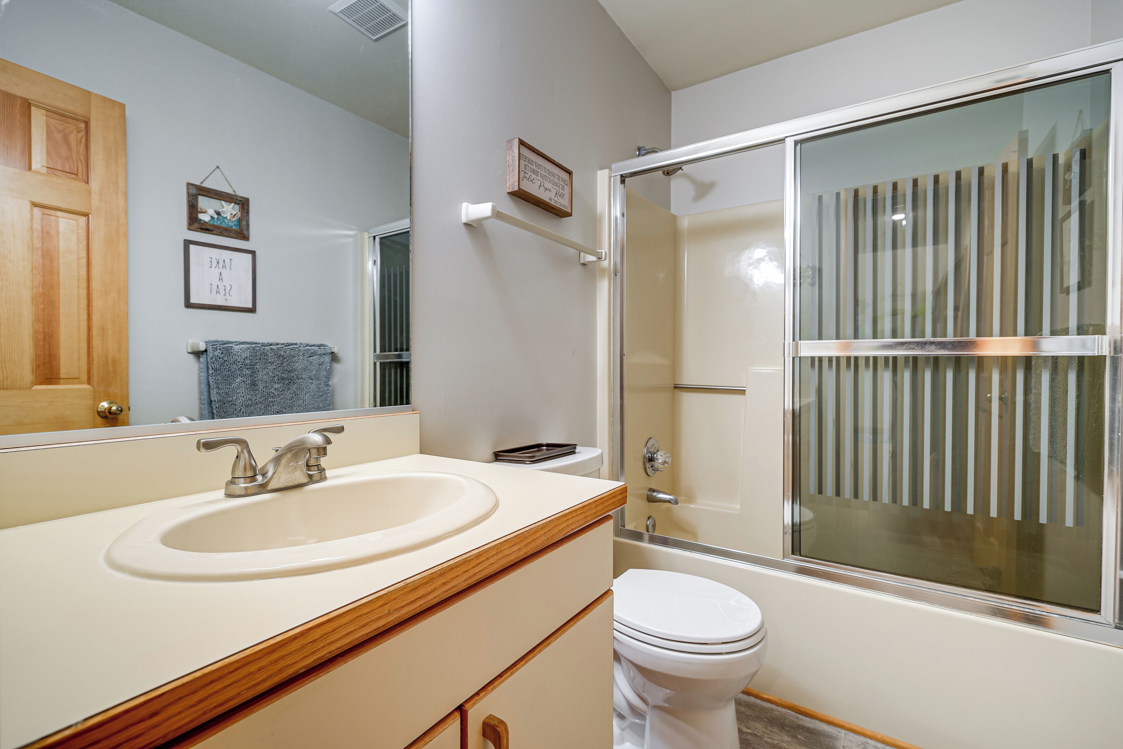 A bathroom with a sink, mirror, toilet, and a glass-enclosed shower.