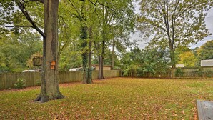 A backyard with a wooden deck, a large tree, and a fence.