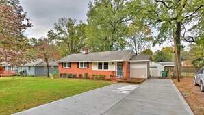 A single-story house with a brick facade, a front porch, and a driveway leading to the garage.
