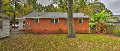 A single-story brick house with a front yard covered in fallen leaves.