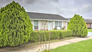 A residential house with a well-maintained lawn, two large coniferous trees, and a clear sky. - Apartment w/ Patio: 15 Miles to French Quarter! (Westwego)