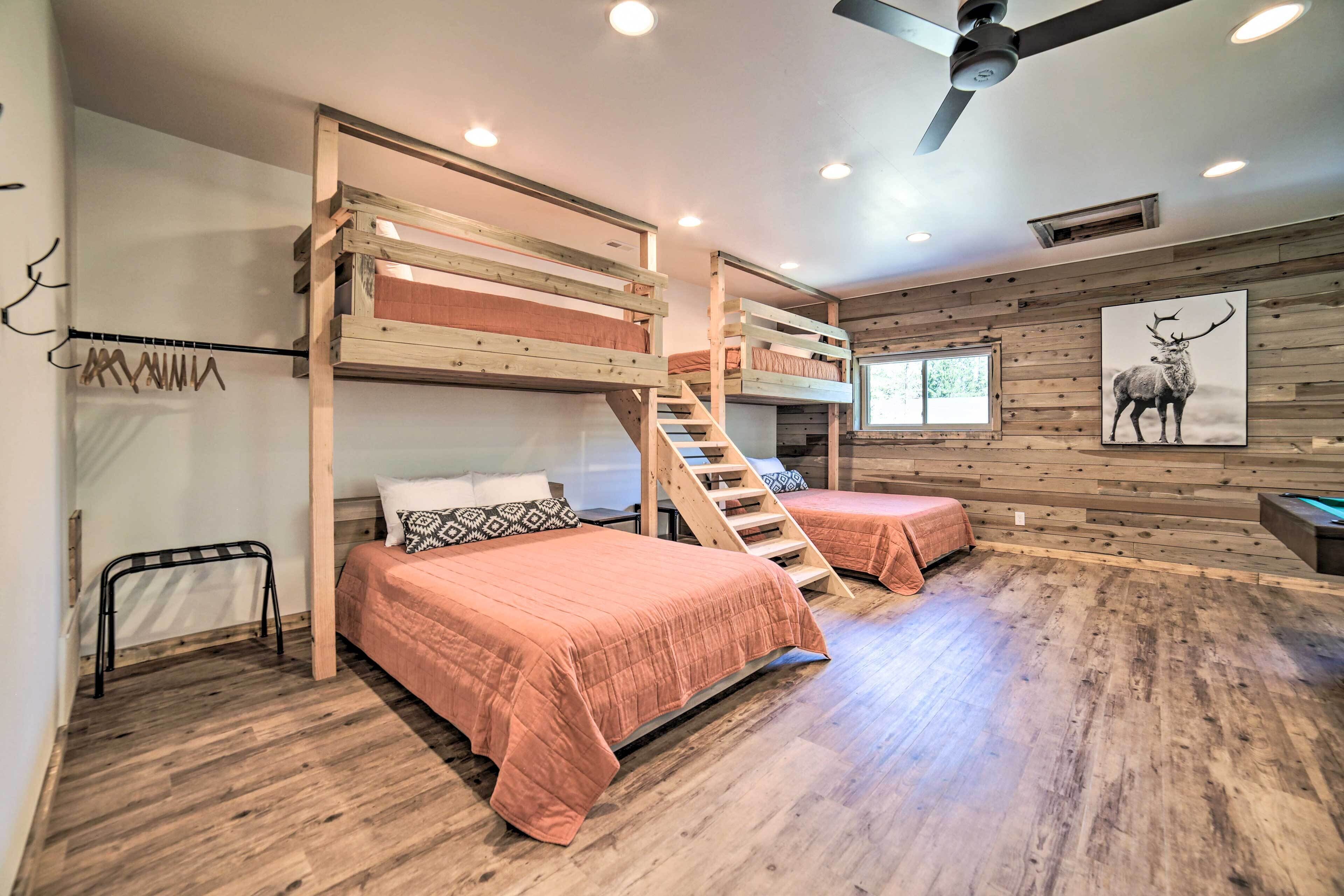 A bunk bed room with a wooden ceiling fan, a staircase, and a deer picture on the wall.