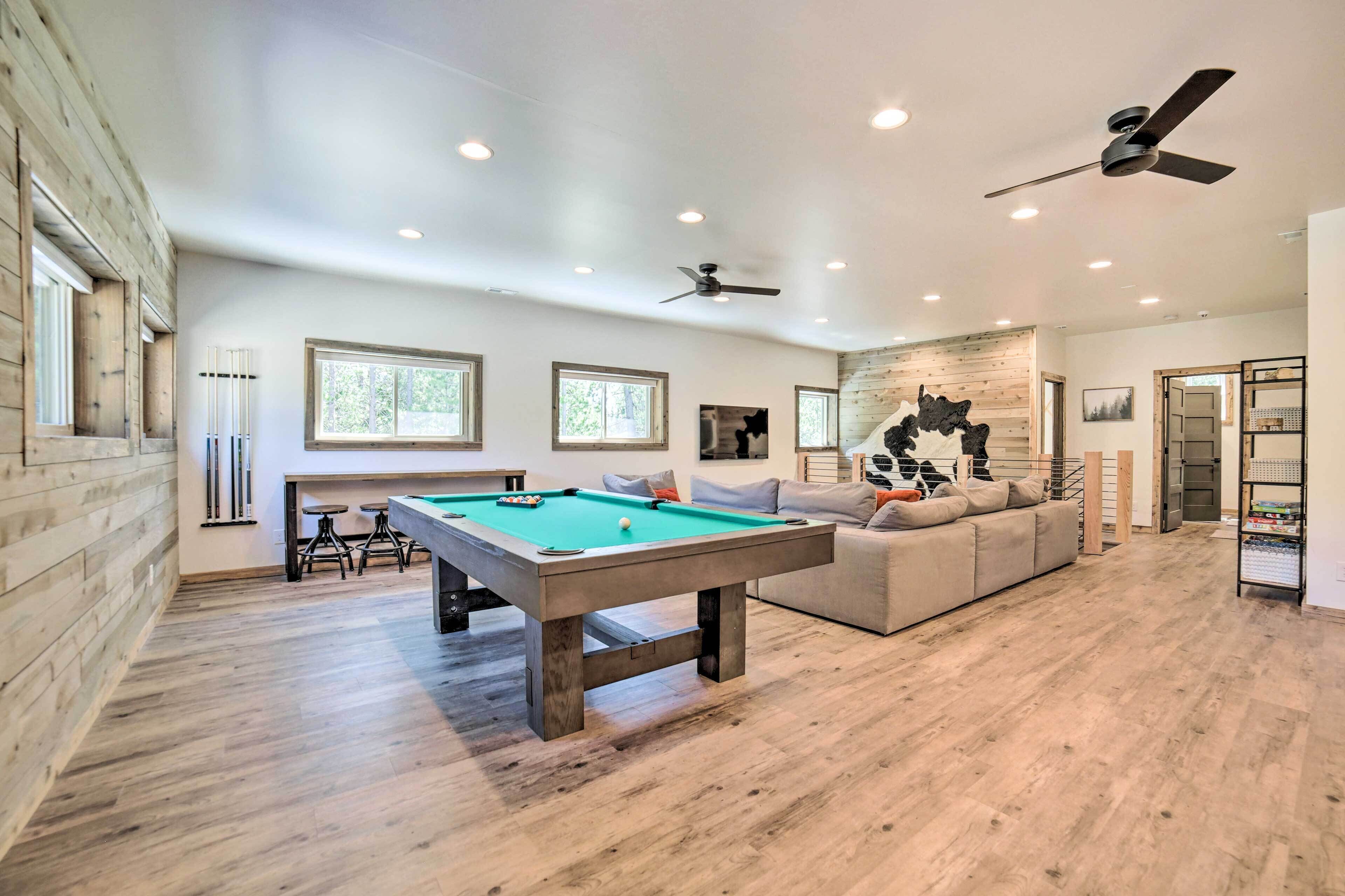 Une pièce spacieuse équipée d’une table de billard, d’un canapé et d’un ventilateur de plafond.