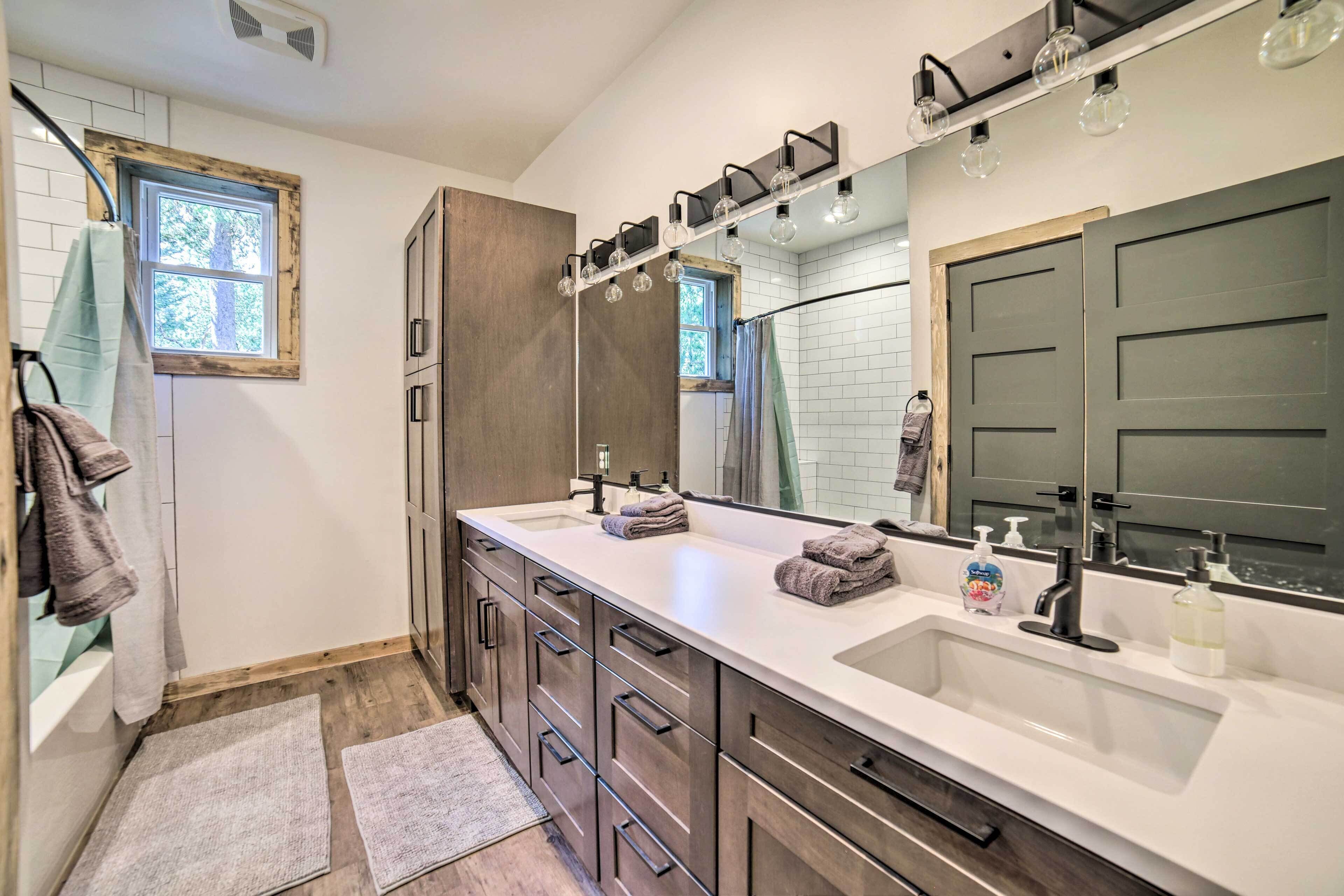 Un baño moderno con lavamanos doble, muebles de madera y un espejo grande.