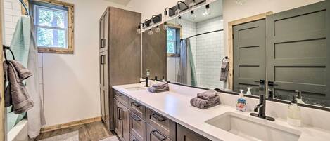 Un baño moderno con lavamanos doble, muebles de madera y un espejo grande.