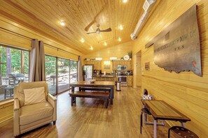 Ein geräumiger Raum mit Holzboden, einem Essbereich mit Tisch und Bänken, einer Couch und Blick durch große Fenster.