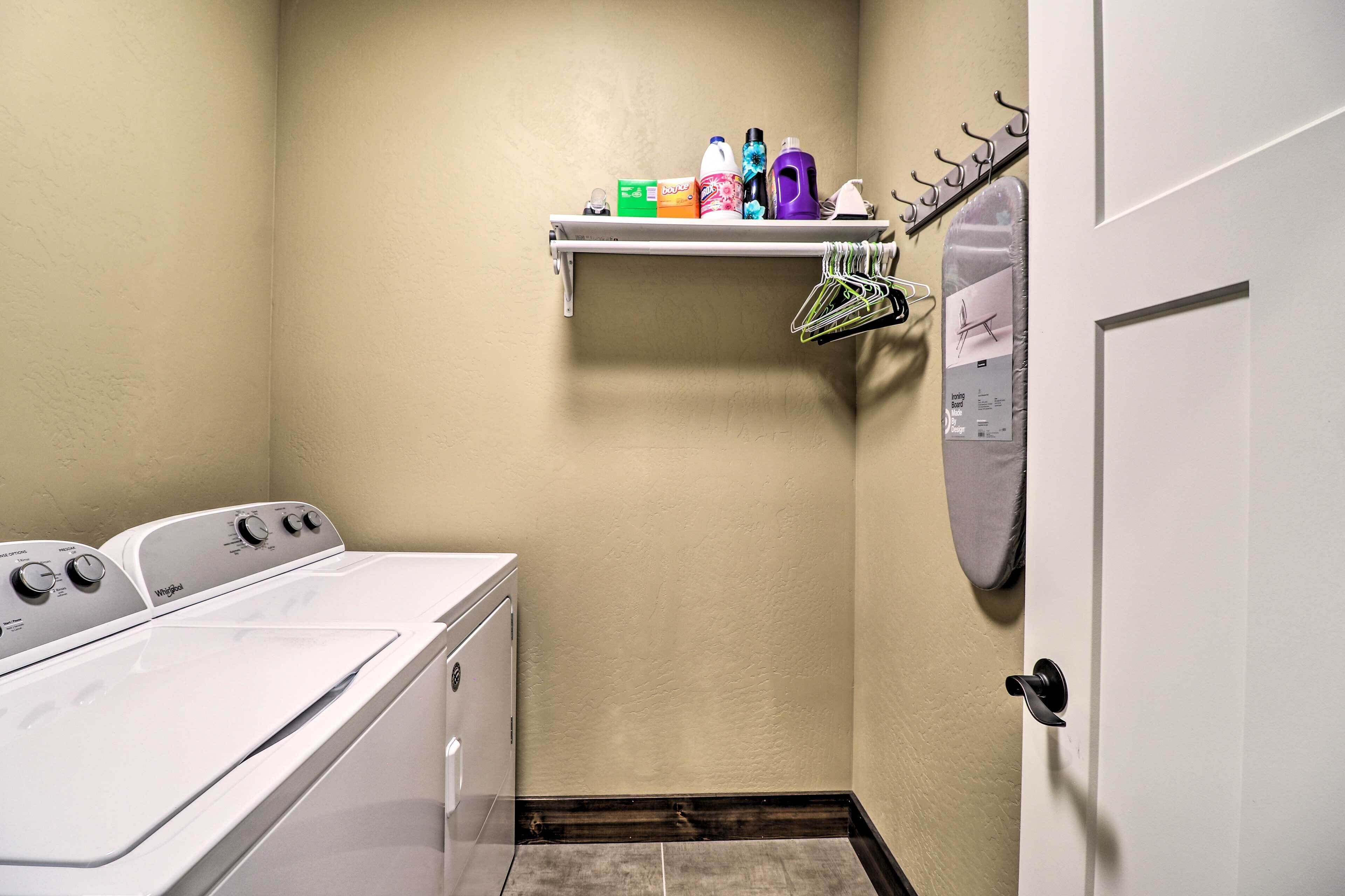 A laundry room with a washing machine, dryer, and a shelf with cleaning supplies.