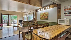 A spacious kitchen with wooden furniture, a dining area, and a view of the outdoors. - Charming Laconia Home w/ Deck: Walk to Lake! (Laconia)